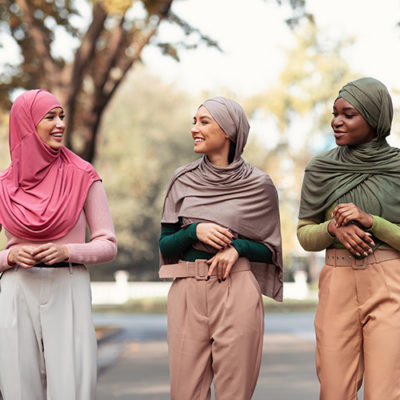 Three,Modern,Muslim,Young,Women,In,Hijab,Headscarf,Walking,In Three Modern Muslim Young Women In Hijab Headscarf Walking In Park Outdoors. Cheerful Islamic Students Ladies Talking Enjoying Walk Outside. Female Frienship, Fashion Concept
